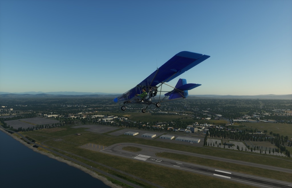 A screenshot from X-Plane 12 of an ultralight plane over Portland's airport in the late afternoon.